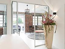 Wartezimmer mit Backsteinwänden, großem Blumenkübel und moderner Einrichtung